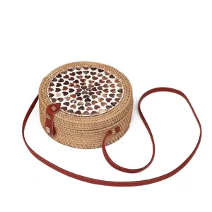 Runde Rattan Umhängetasche mit Muschel Herz Inlay und rotem Lederriemen im Vintage-Stil.