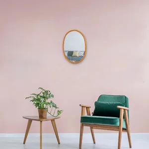 Scatto di dettaglio dello specchio da parete ovale in rattan con cornice naturale in un interno.