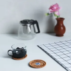 Handwoven rattan coaster with ceramic center, natural tea cup mat for home kitchen decor.