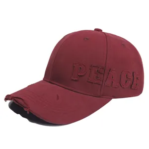 Detailopname van de versleten klep en geborduurde PEACE-letter op de bordeaux pet.