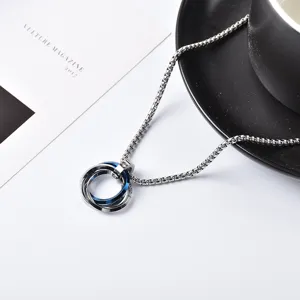 Primer plano detallado del collar con colgante de acero titanio de tres anillos en fondo blanco.