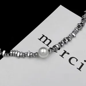 Detail close-up view of the unique irregular metallic stone and pearl spliced necklace.