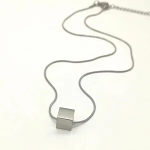 Detail shot of minimalist titanium steel cube pendant necklace on delicate snake chain.