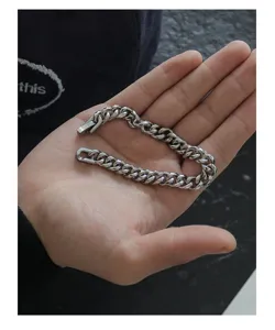 Detailed shot of a stylish silver Cuban link bracelet held in hand, metal texture and close-up.