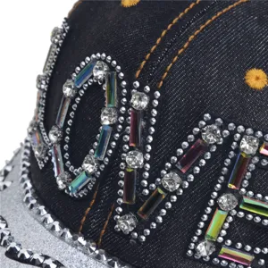 Detailopname van een zwarte denim honkbalpet met fonkelende strass-steentjes en letters.