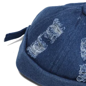 Detailopname van de blauwe denim docker muts voor heren met trendy gescheurd design.