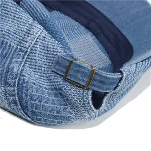Close-up detail of vintage denim flat cap back featuring adjustable metal buckle and texture.