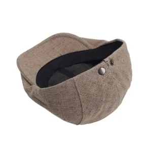 Close-up detail of the brown wool flat cap showing interior lining and metal snap button.