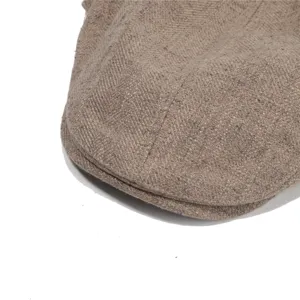 Close-up detail of a vintage style khaki newsboy cap showing textured fabric weave.