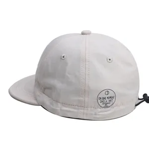 Beige retro korte rand honkbalpet detail, zachte pet met verstelbaar koord en opdruk.