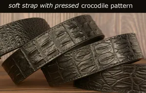 Close-up detail of black leather belt with pressed crocodile pattern and soft strap texture.