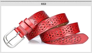 Closeup of red leather belt featuring intricate hollow-out floral patterns and shiny metal buckle.