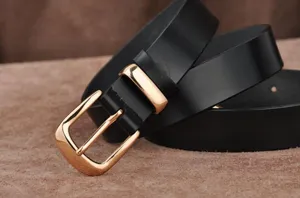 Close-up detail of women's black leather belt with a shiny gold metal buckle, stylish and classic.