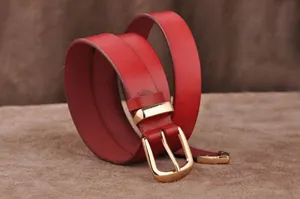 Red leather belt detail showing smooth texture, gold metal pin buckle and stylish loop design.