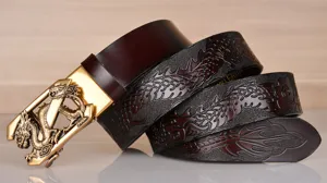 Detailed view of men leather belt with embossed dragon pattern and gold automatic buckle.