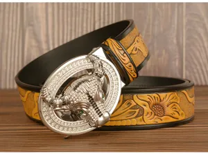 Detail view of men's leather belt featuring a sparkling rhinestone bull head buckle and embossed pattern.