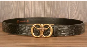 Detail view of mens black crocodile pattern leather belt featuring a gold bull head buckle.