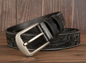 Detailed view of embossed leather men's belt with stylish carved floral pattern and metal buckle.