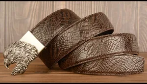 Detailed view of mens leather belt with crocodile embossed pattern and eagle buckle.