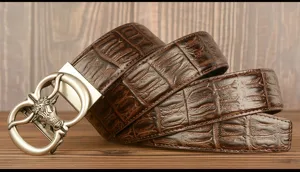 Detailed view of brown crocodile embossed leather men's belt with stylish bull head buckle.