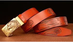 Close-up of men's leather belt with metallic eagle buckle and embossed eagle pattern.