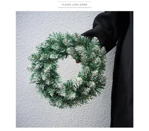 Detail shot of snow-tipped green Christmas wreath for holiday door decor and tree hanging.
