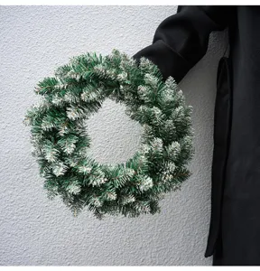 Snow-tipped artificial green Christmas wreath for holiday home door hanging and tree decoration.