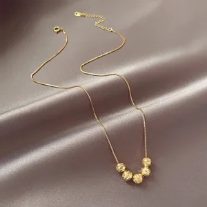 Vue détaillée du collier élégant en acier au titane doré avec des pendentifs perles étincelants.