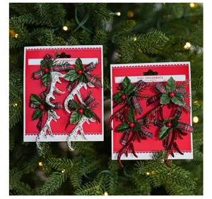 Detail van mini kerstgewei ornamenten met ruitjesstrikken en groene hulstbladeren op rode kaart.