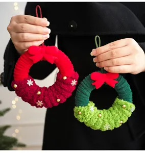 Gros plan de couronne de Noël en peluche artisanale, avec jolis nœuds et cloches festives.