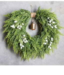 Kunstmatige kerst ceder krans met witte bessen en metalen bel voor voordeur decoratie.