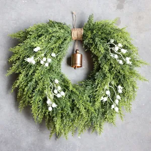 Kunstkerstkrans van cederhout met bel en witte bessen voor decoratie van de voordeur