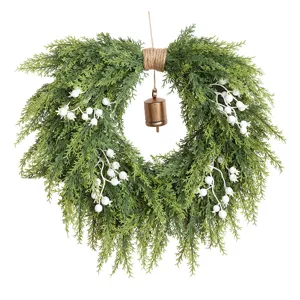 Kerst ceder krans met witte bessen en hangende bel, voordeur decoratie voor feestdagen.