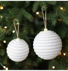 Primer plano detallado de adornos navideños colgantes envueltos en cuerda con cordel natural.