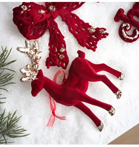 Primo piano di ornamenti natalizi rossi floccati a forma di cervo e fiocco con glitter.