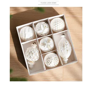 Detailed display of luxury white and gold Christmas tree hanging ornaments in gift box.