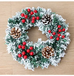 Weihnachtskranz künstlich mit Schneebeflockung, Tannenzapfen und roten Beeren für Deko.