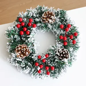 Weihnachtskranz mit schneebedeckten Tannennadeln, Zapfen und roten Beeren für die Feiertage