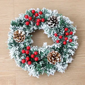 Festlicher beflockter Weihnachtskranz mit künstlichen Tannenzapfen und roten Beeren.