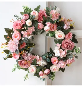 Gros plan détaillé d'une couronne de fleurs artificielles avec roses roses et pivoines.