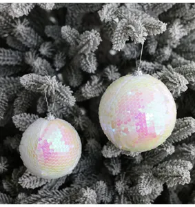 Primer plano detallado de bolas de Navidad iridiscentes colgando en ramas de abeto nevadas.