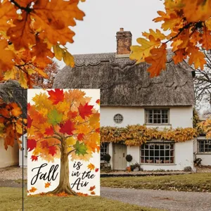 Detail shot of decorative garden flag featuring autumn tree and text, hanging in yard.
