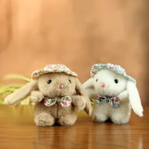 Primo piano di adorabili ciondoli di coniglio in peluche con cappelli floreali sul tavolo.