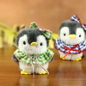 Dettaglio del portachiavi pinguino in peluche con pelliccia morbida e abito a quadri.