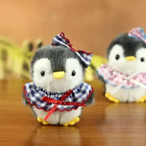 Dettaglio del peluche pinguino carino con trama morbida e mantellina a quadretti.