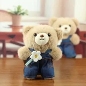 Joli pendentif en peluche d'ours en jean bleu avec une petite fleur blanche.