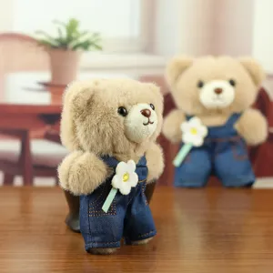 Vue détaillée d'un charmant pendentif en peluche d'ours en salopette en jean avec fleur.