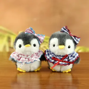 Dettaglio del ciondolo pinguino di peluche con bavaglino a quadretti e fiocco carino.
