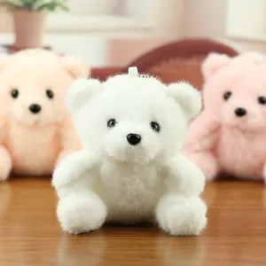 Close-up van een schattige mini witte pluche teddybeer sleutelhanger met zachte vacht en ketting.