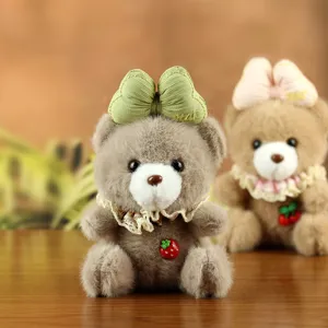 Cute plush teddy bear pendant with bow and strawberry charm, soft stuffed toy for backpack decor.